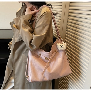 Lifestyle view of pink faux leather hobo bag with cute bear charm and golden hardware detail