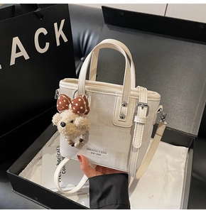 Gros plan du sac seau crème texturé avec une charmante décoration d'ours en peluche