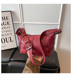 Detail of red retro hobo bag with leather texture and star metal decor on adjustable strap