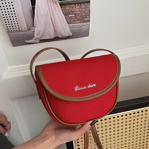 Detail of red canvas saddle bag with brown leather trim and Luuuu store lettering