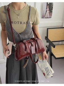 Close-up of a vintage dark red leather shoulder bag with buckle details worn by a model
