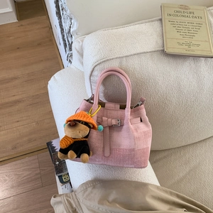 Detail der rosa Tweed-Beuteltasche mit Ledergriff und süßem Welpen-Plüschanhänger