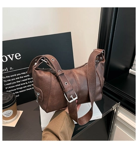 Detail of dark brown leather texture and adjustable shoulder strap with silver buckle