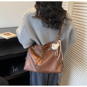 Macro shot of brown retro faux leather tote bag texture with decorative strap and bear charm
