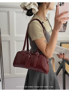 Close-up of a vintage burgundy patent leather Boston bag with silver zipper and charm