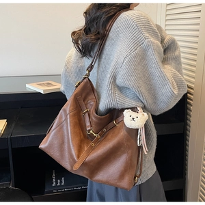 Close-up of vintage brown tote bag texture with metallic buckle and plush bear charm
