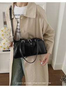 Close-up of elegant black glossy Boston bag worn with a stylish beige trench coat