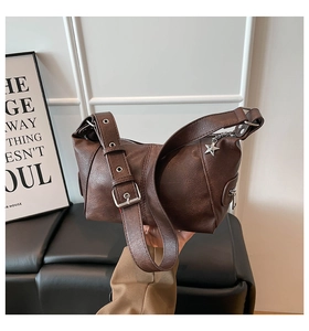 Detail of vintage brown shoulder bag with silver grommets and a star-shaped metal pendant
