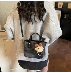 Détail du sac cabas gris à carreaux avec breloque ours et bandoulière en cuir noir