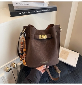 Detail of a vintage dark brown bucket bag with gold clasp and retro wooden bead charm