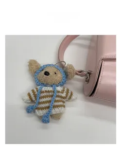 Detail of cute plush bear charm with striped sweater attached to pink handbag