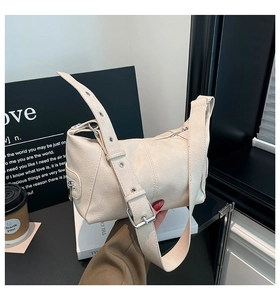 Detail of the cream dumpling bag featuring adjustable wide strap and metallic eyelets