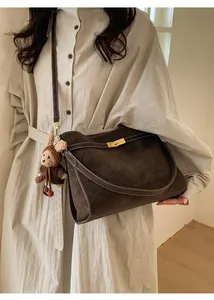 Détail du sac cabas en daim marron foncé avec fermoir doré et surpiqûres blanches