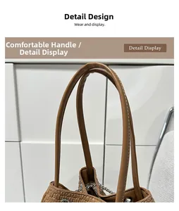 Detail view of the brown woven bucket bag featuring a sturdy leather handle and chain accents
