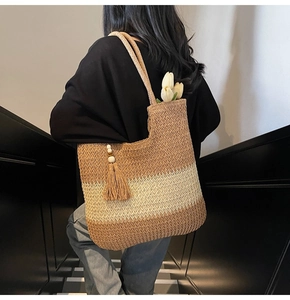 Detail of a woven straw beach tote featuring tri-color panels and wood bead tassels