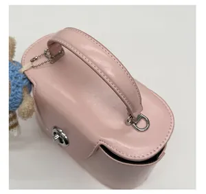 Close-up of pink crossbody box bag with silver lock and a cute plush bear charm