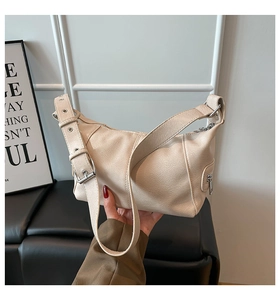 Detail of beige faux leather shoulder bag with adjustable eyelet strap and side zip pocket