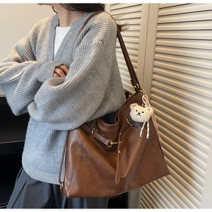 Side view of a vintage dark brown faux leather tote bag with cute plush bear charm
