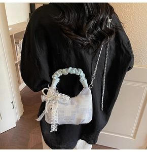 Detail of light blue checkered dumpling bag with ruffled handle and pearl heart charm