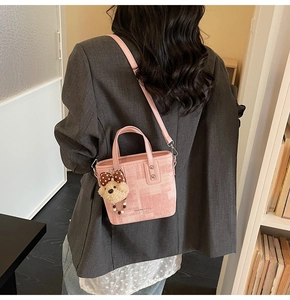 Détail du sac seau en toile rose avec charm ours en peluche et logo sur la bandoulière