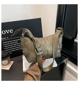 Detail of olive green textured leather handbag with silver buckle and wide shoulder strap