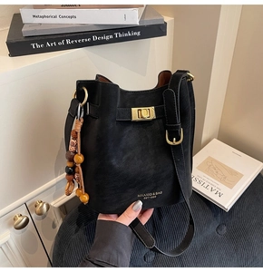 Detail of black matte bucket bag featuring gold clasp and vintage wooden bead charm