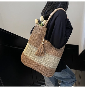 Detail of woven straw tote bag with gradient colors and decorative wooden bead tassels