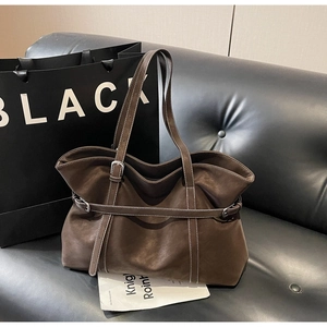 Detail of vintage brown tote bag with white contrast stitching and buckle strap decoration