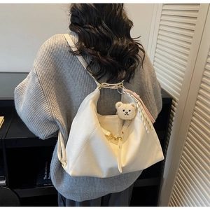 Detail of white oversized tote bag with plush bear charm and soft leather texture