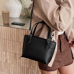 Detail of black lychee grain bucket bag with dual handles and silver metal strap