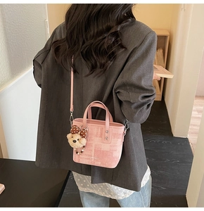 Détail d'un sac seau rose à texture géométrique avec breloque d'ours en peluche doux