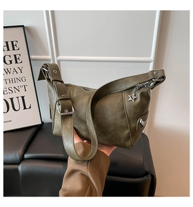 Close-up of olive green vintage leather bag with silver star pendant and eyelet strap