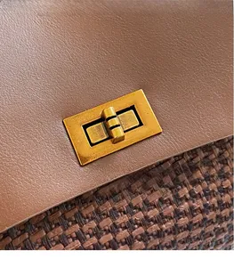 Detail of vintage gold metal lock on brown leather and woven textured shoulder bag