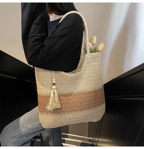 Detail of woven straw tote bag with side tassels and beads in resort beach style