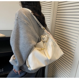 Detail of white leather tote with decorative floral scarf and cute plush bear charm accessory