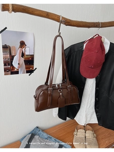 Artistic display of dark brown oil-wax leather shoulder bag hanging on a wooden hook