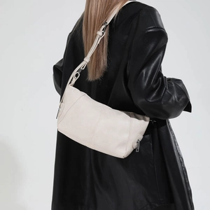 Close-up of cream leather shoulder bag with metal zipper detail on adjustable strap
