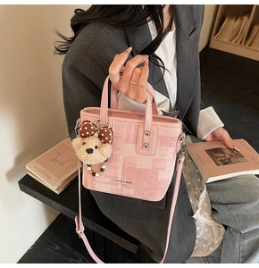 Détail du sac seau en tricot rose avec breloque ours en peluche et anses en cuir