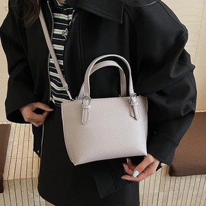 Close-up of a light grey pebble leather bucket bag with top handles and shoulder strap