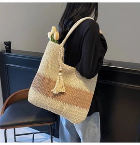 Close-up of woven straw tote bag featuring tassels, wooden beads and a color-block design