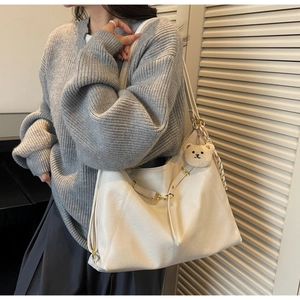 Detail of white PU leather tote bag with fluffy bear charm and striped silk scarf decor