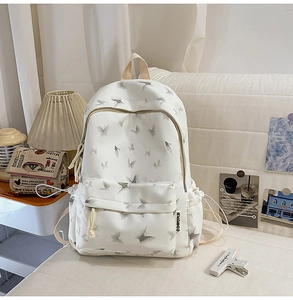 Close-up of white nylon backpack with butterfly print and side drawstring pocket detail