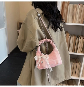 Detailed shot of pink pleated dumpling bag with lace bow, pearls and heart pendant