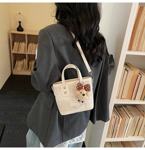 Détail du sac seau en tissu blanc cassé avec un charmant ours en peluche et un nœud à pois