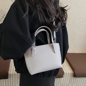 Detail of light gray bucket bag with lychee texture and adjustable shoulder strap