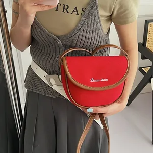 Detailed view of red canvas saddle bag with leather trim and adjustable crossbody strap