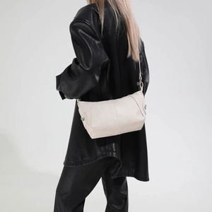 Macro view of creamy off-white hobo bag with leather texture and silver buckle detail
