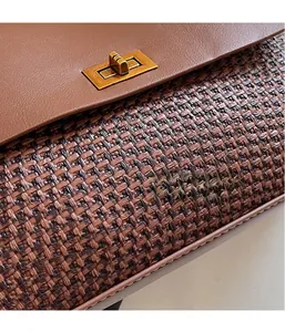 Close-up of retro brown handbag featuring smooth leather and woven texture with metal lock