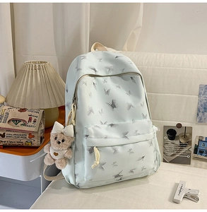 Close-up of light blue nylon backpack with butterfly print and cute bear plush charm
