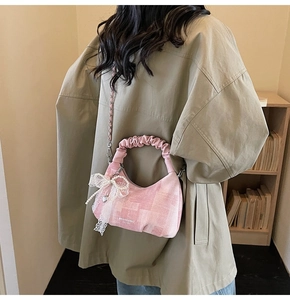 Pink dumpling bag detail with pleated handles, lace bow, and silver metal chain